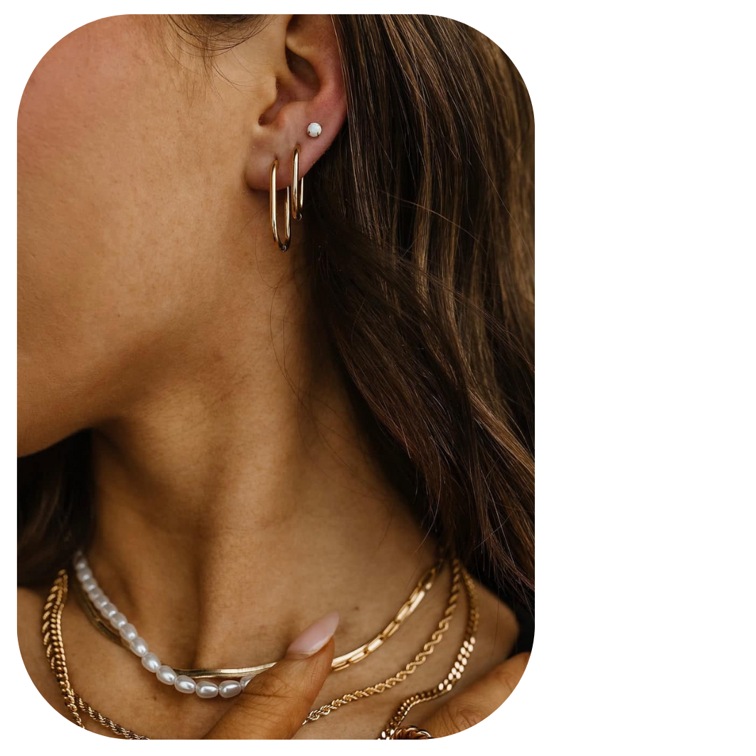 Close-up of a woman's ear with multiple piercings featuring a small stud and two gold hoops, partially overlaid with a pink flower graphic. Stylish ear piercing options shown by Peekaboo Piercing in Tampa.