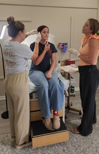 Mobile ear piercers in Tampa providing simultaneous earlobe piercings for a client during a private party setup.